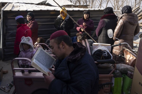 An iman reads from the Quran as family members gather for the burial of Han Suofeiya who was killed in an earthquake in Yangwa village near Dahejia town in northwestern China's Gansu province, Wednesday, Dec. 20, 2023. (AP Photo/Ng Han Guan)