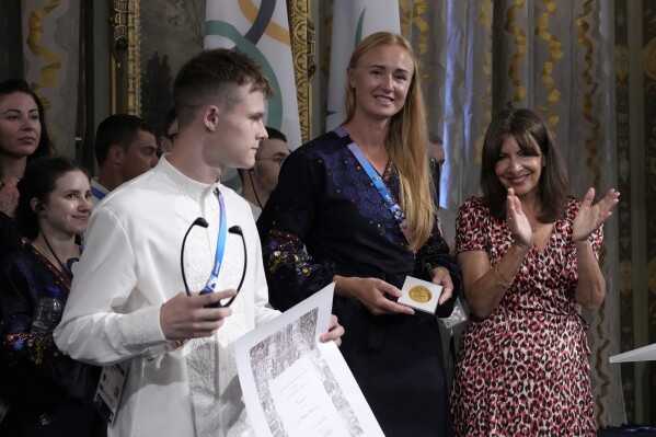 Paris mayor Anne Hidalgo, right, applauds after awarding Ukrainian athletes Oleskii Sereda and Anastasiia Kozhenkova, center, during a ceremony at the 2024 Summer Olympics, Thursday, Aug. 1, 2024, in Paris, France. Hidalgo awarded the whole Ukrainian delegation with the Medal of the City of Paris.(AP Photo/Michel Euler)