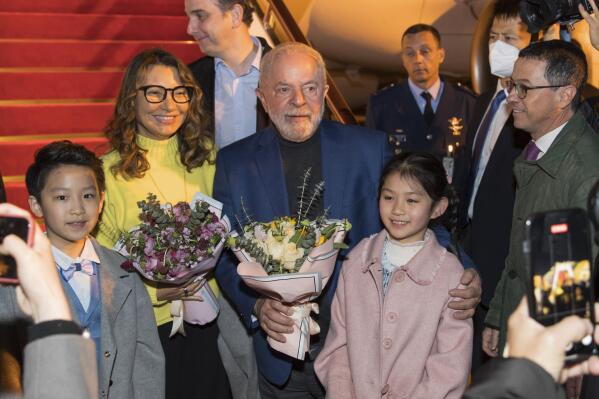 In this photo released by Xinhua News Agency, Brazilian President Luiz Inacio Lula da Silva, center, and first lady Rosangela Silva, second left, receive flowers presented by children from the Shanghai Children's Palace of the China Welfare Institute upon arrival in Shanghai, China on Wednesday, April 12, 2023. Lula was in the Chinese financial hub of Shanghai on Thursday in a bid to boost ties with the South American giant's biggest trade partner and win political support for attempts to mediate the conflict in Ukraine. (Gao Feng/Xinhua via AP)
