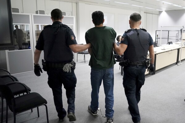 FILE - The defendant Ibrahim A. is brought into the courtroom in handcuffs, in Itzehoe, Germany, Monday April 15, 2024. A court on Wednesday, May 15, 2024, convicted Ibrahim of murder and sentenced him to life in prison for carrying out a fatal stabbing on a train in northern Germany last year. (Marcus Brandt/Pool via AP, File)