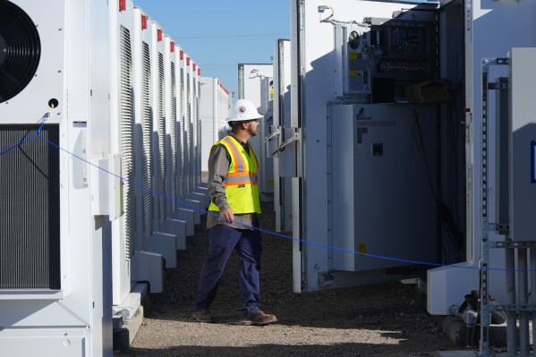 A worker does checks on battery storage pods at Orsted's Eleven Mile Solar Center lithium-ion battery storage energy facility Thursday, Feb. 29, 2024, in Coolidge, Ariz. Batteries allow renewables to replace fossil fuels like oil, gas and coal, while keeping a steady flow of power when sources like wind and solar are not producing. (AP Photo/Ross D. Franklin)