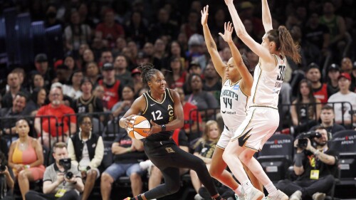 Las Vegas Aces guard Chelsea Gray (12) is guarded by New York Liberty forward Betnijah Laney (44) and forward Breanna Stewart (30) during the first half of a WNBA basketball game Thursday, June 29, 2023, in Las Vegas. (Steve Marcus/Las Vegas Sun via AP)