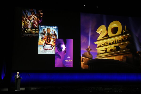 FILE - In this April 3, 2019, file photo, Alan Horn, chairman of The Walt Disney Studios, speaks underneath poster images for 20th Century Fox films during the Walt Disney Studios Motion Pictures presentation at CinemaCon 2019, the official convention of the National Association of Theatre Owners (NATO) at Caesars Palace in Las Vegas. Disney is dropping the word “Fox” from the movie studios it acquired as part of last year's $71 billion purchase of Fox's entertainment business, according to published reports. According to trade publication Variety, 20th Century Fox will become 20th Century Studios, while Fox Searchlight Pictures will be Searchlight Pictures. Disney will still run them as separate studios within the company. (Photo by Chris Pizzello/Invision/AP, File)