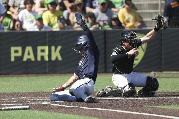Oral Roberts utility Jonah Cox, left, slides home to score past Oregon catcher Bennett Thompson, right, during the third inning of an NCAA college baseball tournament super regional game Sunday, June 11, 2023, in Eugene, Ore. (AP Photo/Amanda Loman)