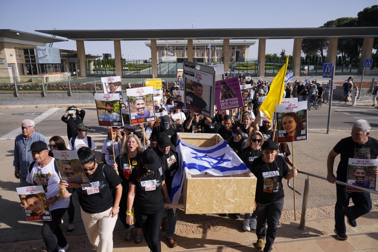 Familiari e attivisti trasportano una bara vuota durante un finto funerale tenuto prima del Giorno della Memoria per gli israeliani i cui resti sono trattenuti dai militanti di Hamas nella Striscia di Gaza, vicino al palazzo del parlamento israeliano a Gerusalemme, giovedì 9 maggio 2024. Giorno della Memoria è sempre un'occasione cupa in Israele.  Ma sulla scia degli eventi del 7 ottobre, la crisi ha assunto un carattere profondo e aspro di tristezza unito a una rabbia dilagante.  (AP Photo/Ohad Zwegenberg)