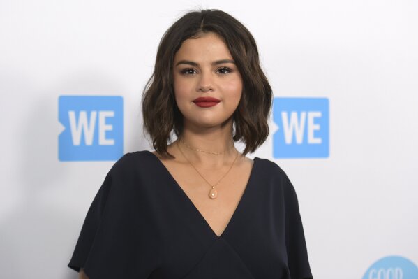 FILE - Selena Gomez arrives at WE Day California on April 19, 2018, in Inglewood, Calif. Gomez is taking the heat in the kitchen. The singer-actress slices and dices in “Selena + Chef,” debuting Aug. 13 on the new HBO Max streaming service. The 10-episode series was shot in the kitchen of Gomez’s new Los Angeles-area house. Her grandparents and two friends, who have been quarantining with her, serve as taste testers. (Photo by Richard Shotwell/Invision/AP, File)