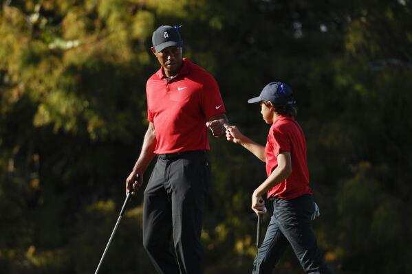 Tiger Woods fist bumps his son Charlie Woods on the 16th green during the second round of the PNC Championship golf tournament, Sunday, Dec. 19, 2021, in Orlando, Fla. (AP Photo/Scott Audette)