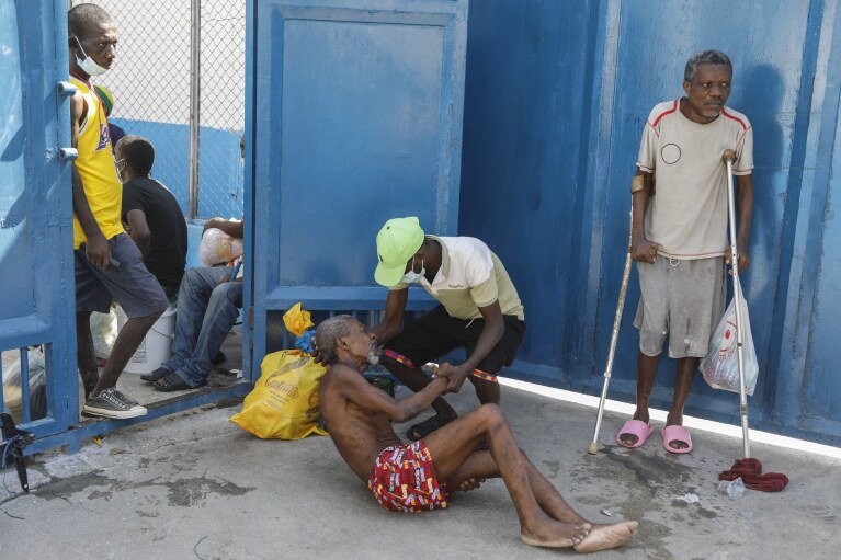 An inmate helps another prisoner inside the National Penitentiary in Port-au-Prince, Haiti, Sunday, March 3, 2024. Hundreds of inmates fled Haiti's main prison after armed gangs stormed the facility overnight. (AP Photo/Odelyn Joseph)
