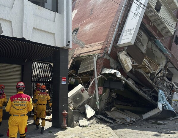 In this photo released by the National Fire Agency, members of a search and rescue team prepare outside a leaning building in the aftermath of an earthquake in Hualien, eastern Taiwan on Wednesday, April 3, 2024. Taiwan's strongest earthquake in a quarter century rocked the island during the morning rush Wednesday, damaging buildings and creating a tsunami that washed ashore on southern Japanese islands. (National Fire Agency via AP)