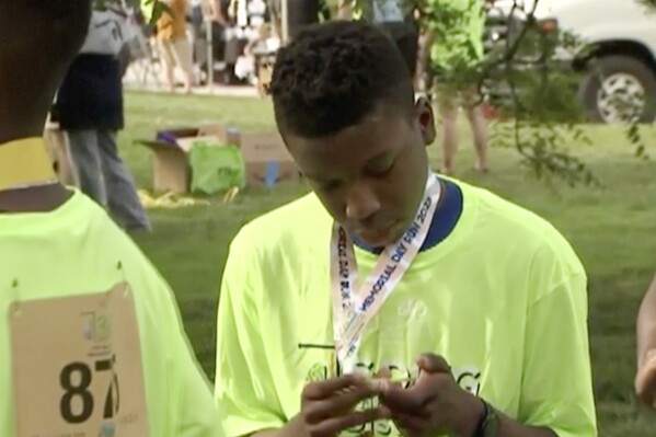 FILE - Ralph Yarl looks at a badge that he received after walking at a brain injury awareness event on Monday, May 29, 2023 in Kansas City, Mo. Yarl tells ABC's “Good Morning America” on Tuesday, June 27, that he never thought he would be shot even after the white man at the door he had mistakenly knocked on in Kansas City pointed a gun at him. Yarl was shot in the head and arm in April, after mistakenly ringing the wrong doorbell. (KCTV via AP)