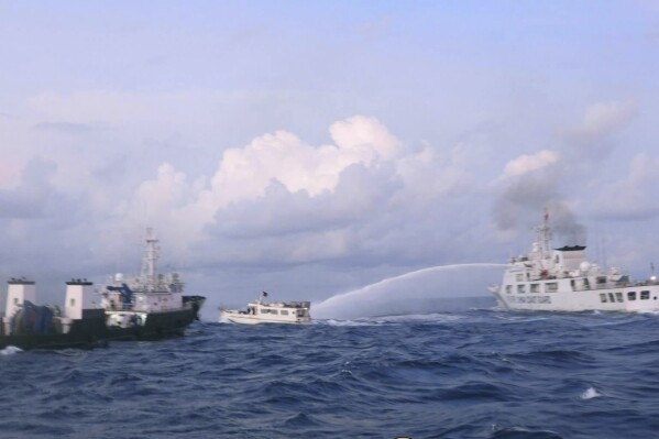 In this handout photo provided by the Philippine Coast Guard, a Chinese Coast Guard ship uses water cannons on Philippine navy-operated supply boat M/L Kalayaan as it approaches Second Thomas Shoal, locally known as Ayungin Shoal, in the disputed South China Sea on Sunday Dec. 10, 2023. The Chinese coast guard targeted Philippine vessels with water cannon blasts Sunday and rammed one of them, causing damage and endangering Filipino crew members off a disputed shoal in the South China Sea, just a day after similar hostilities at another contested shoal, Philippine officials said.(Philippine Coast Guard via AP)