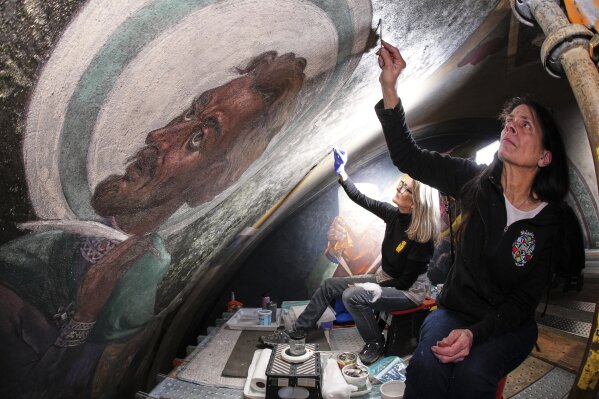 Art conservation technician Celeste Parrendo, right, works on a mural by Maxo Vanka that depicts St. Matthew, inside St. Nicholas Croatian Catholic Church in Millvale, Pa., Feb 13, 2025. (AP Photo/Gene J. Puskar