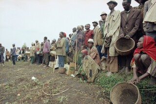 Tutsis refugees wait for food distribution by relief agencies at the camp run by the French military in Bisesero, 40 miles southwest of Kigali on Saturday, July 2, 1993. The French troops are protecting the civilians from armed Hutus who can be seen waiting outside the camp. (AP Photo/Jean-Marc Bouju)
