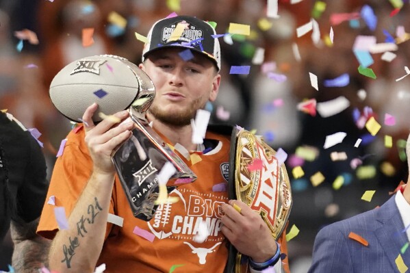 Texas quarterback Quinn Ewers blows a kiss to the trophy as he celebrates after the Big 12 Conference championship NCAA college football game against Oklahoma State in Arlington, Texas, Saturday, Dec. 2, 2023. (AP Photo/Tony Gutierrez)