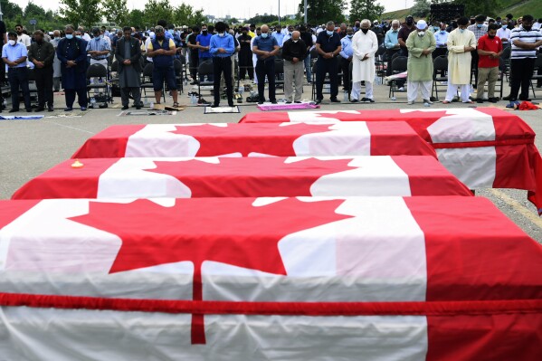 FILE - Mourners pray as caskets draped in Canadian flags are lined up at a funeral for the four Muslim family members killed in a deadly vehicle attack, at the Islamic Centre of Southwest Ontario in London, Ontario, on Saturday, June 12, 2021. Canadian federal prosecutors argued that a man facing murder charges in the deaths of four members of a Muslim family was motivated by white nationalist beliefs as they branded the attack an act of terrorism. (Nathan Denette/The Canadian Press via AP, Pool, File)