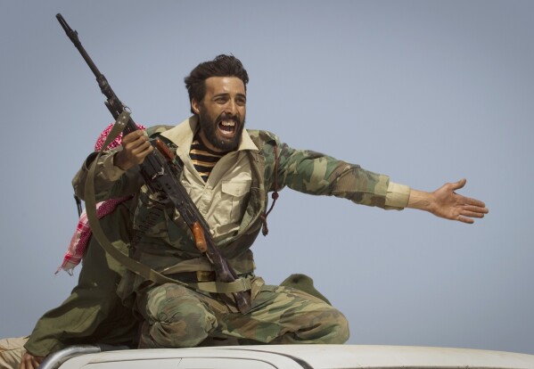A Libyan rebel urges people to leave as shelling from Gadhafi's forces starts landing on the frontline outside of Bin Jawaad, 150 kilometers (93 miles) east of Sirte, central Libya, on March 29, 2011. (AP Photo/Anja Niedringhaus, File)
