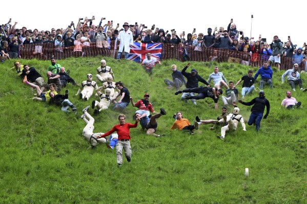 Participants compete in the men's downhill race category of the traditional annual Cheese Rolling contest at Cooper's Hill in Brockworth, Gloucestershire, England, Monday, May 26, 2025.(AP Photo/Anthony Upton)