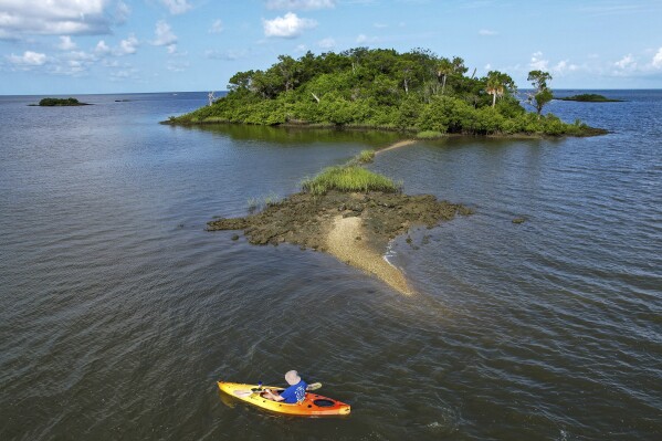 Associated Press reporter Richard Lardner kayaks to Sweetheart Island, off the coast of Yankeetown, Fla., on Aug. 5, 2023. Patrick Parker Walsh is serving five and half years in federal prison for stealing nearly $8 million in federal COVID-19 relief funds that he used, in part, to buy the island. (AP Photo/Julio Aguilar)