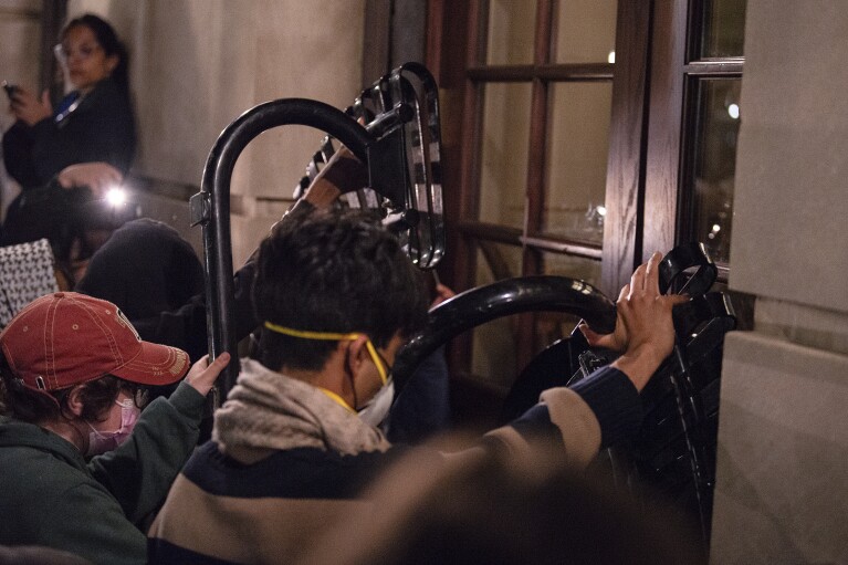 Students with the Gaza solidarity encampment block the entrance of Hamilton Hall at Columbia University after taking over it on Tuesday, April 30, 2024 in New York. Columbia Students for Justice in Palestine called for mobilization close to midnight. (Marco Postigo Storel via AP)