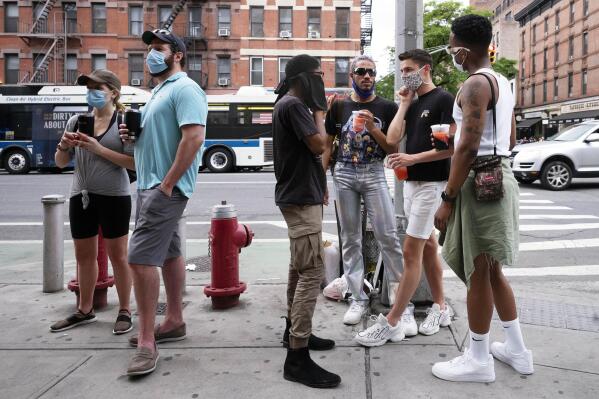 FILE — People gather on a street in the Hell's Kitchen neighborhood of New York while waiting to get takeout drinks at a bar, May 29, 2020. (AP Photo/Mark Lennihan, File)