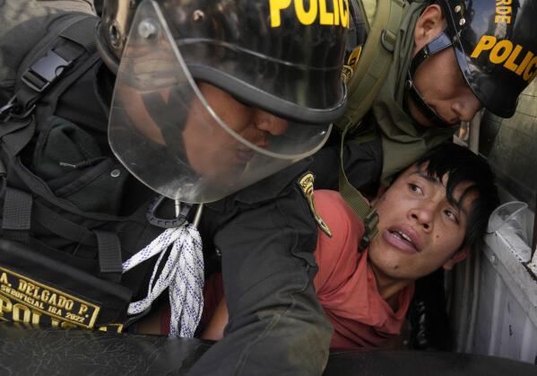 An anti-government protesters who traveled to the capital from across the country to march against Peruvian President Dina Boluarte, is detained and thrown on the back of police vehicle during clashes in Lima, Peru, Thursday, Jan. 19, 2023. Protesters are seeking immediate elections, Boluarte's resignation, the release of ousted President Pedro Castillo and justice for up to 48 protesters killed in clashes with police. (AP Photo/Martin Mejia)