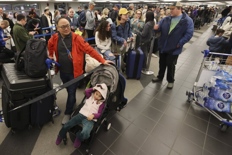Kelvin Lau, left, waits with his family, including daughter Chloe, 3, to rebook a canceled Alaska Airlines flight, Saturday, Jan. 6, 2024, in SeaTac, Wash. (Karen Ducey/The Seattle Times via AP)