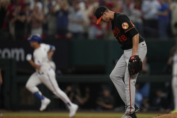 Baltimore Orioles starting pitcher Kyle Gibson (48) walks off the mound as Texas Rangers' Nathaniel Lowe, left, runs the bases with a solo home run in the sixth inning of Game 3 of a baseball AL Division Series on Tuesday, Oct. 10, 2023, in Arlington, Texas. (AP Photo/Julio Cortez)