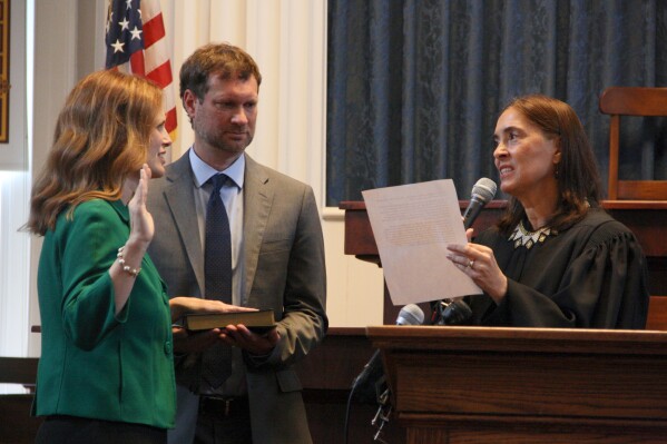 Allison Riggs swears in for her seat on the state Supreme Court as her husband Bryan Everly stands beside her and Associate Justice Anita Earls reads Riggs' oath in the old Capitol building's House chamber in Raleigh, N.C. on Tuesday, May 13, 2025. (AP Photo/Makiya Seminera)