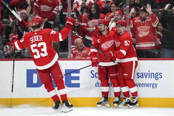 Detroit Red Wings center Dylan Larkin, center, celebrates his goal with Moritz Seider (53) and David Perron (57) in the second period of an NHL hockey game against the Calgary Flames Thursday, Feb. 9, 2023, in Detroit. (AP Photo/Paul Sancya)