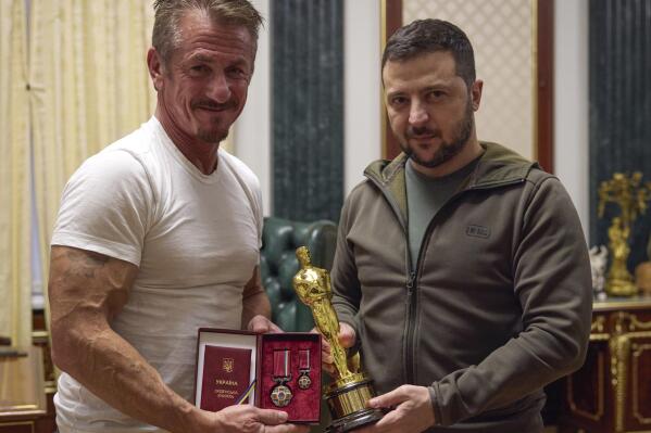 In this photo provided by the Ukrainian Presidential Press Office, Ukrainian President Volodymyr Zelenskyy, right, poses with U.S. actor Sean Penn after receiving latter's Oscar statuette and handing him the Order of Merit, III degree during their meeting in Kyiv, Ukraine, Tuesday, Nov. 8, 2022. (Ukrainian Presidential Press Office via AP)