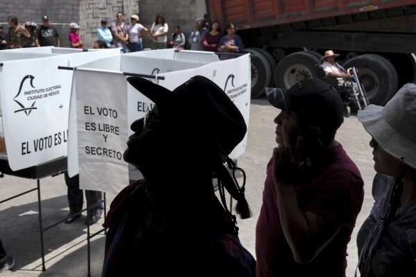 Voters stand in line as they wait their turn to cast their ballots, during general elections in Mexico City, Sunday, June 2, 2024. (AP Photo/Matias Delacroix)