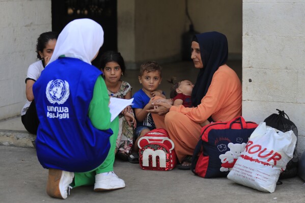 An UNRWA (The United Nations Relief and Works Agency) staff registers a Palestinian family who fled their house in the Palestinian refugee camp of Ein el-Hilweh to an UNRWA school, in the southern port city of Sidon, Lebanon, Tuesday, Sept. 12, 2023. UNRWA said hundreds of families displaced from Ein el-Hilweh refugee camp have taken shelter in nearby mosques, schools and the Sidon municipality building after the fighting that broke out last Thursday in the camp between Palestinian President Mahmoud Abbas' Fatah group and militant Islamist groups which left several people dead and dozens wounded. (AP Photo/Mohammed Zaatari)