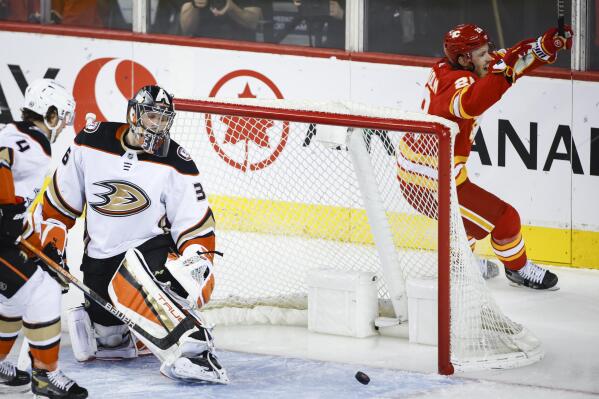 Anaheim Ducks goalie John Gibson, left, reacts as Calgary Flames' Elias Lindholm celebrates his goal during the second period of an NHL hockey game Wednesday, Feb. 16, 2022 in Calgary, Alberta. (Jeff McIntosh/The Canadian Press via AP)