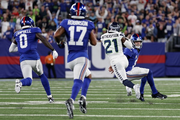 Seattle Seahawks cornerback Devon Witherspoon (21) gets by New York Giants quarterback Daniel Jones (8), wide receiver Parris Campbell (0) and wide receiver Wan'Dale Robinson (17) after intercepting a pass to run it back for a touchdown during the third quarter of an NFL football game, Monday, Oct. 2, 2023, in East Rutherford, N.J. (AP Photo/Adam Hunger)