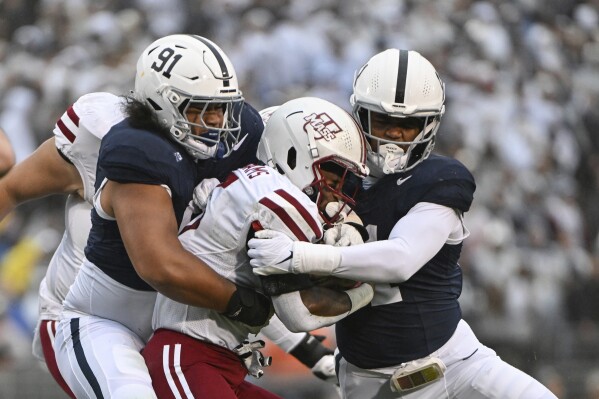 Penn State defenders Dvon Ellies (91) and Abdul Carter (11) tackle Massachusetts running back Kay'Ron Lynch-Adams (15) during the first half of an NCAA college football game against Massachusetts, Saturday, Oct. 14, 2023, in State College, Pa. (AP Photo/Barry Reeger)