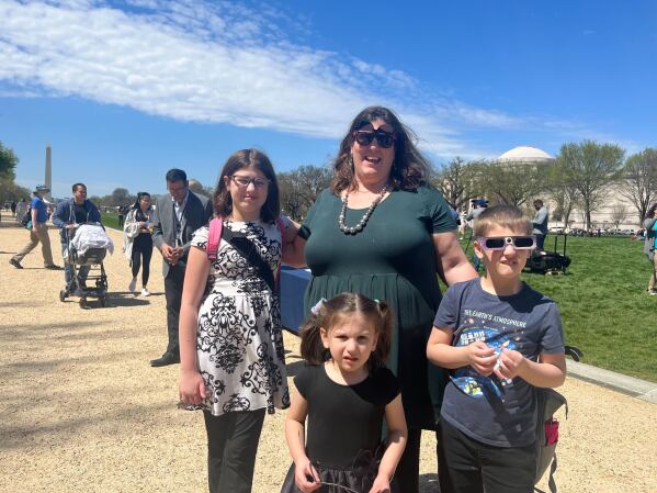 Janice Nozka and her three children picked up their eclipse glasses from a table outside the National Air and Space Museum on the National Mall. (AP Photo/Christina Larson)
