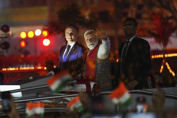 French President Emmanuel Macron, left, and Indian Prime Minister Narendra Modi, with his arm outstretched, ride an open vehicle together during a road show in Jaipur, Rajasthan, India, Thursday, Jan. 25, 2024. Macron will be the chief guest at India's annual republic day parade in New Delhi on Friday. (AP Photo/ Deepak Sharma)