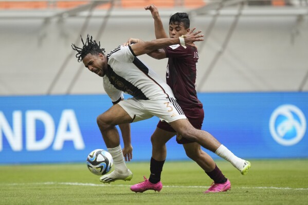 Germany's Almugera Kabar, left, battles for the ball against Venezuela's Junior Colina during their FIFA U-17 World Cup Group F soccer match at Jakarta International Stadium in Jakarta, Indonesia, Saturday, Nov. 18, 2023. (AP Photo/Achmad Ibrahim)