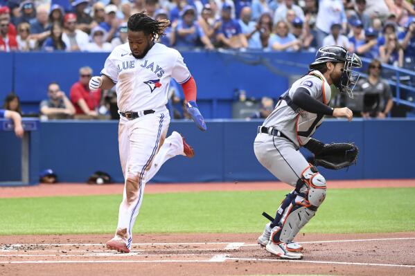 Toronto Blue Jays' Vladimir Guerrero Jr., left, scores on a single by Lourdes Gurriel Jr. in the first inning of a baseball game against the Detroit Tigers in Toronto, Saturday, July 30, 2022. (Jon Blacker/The Canadian Press via AP)