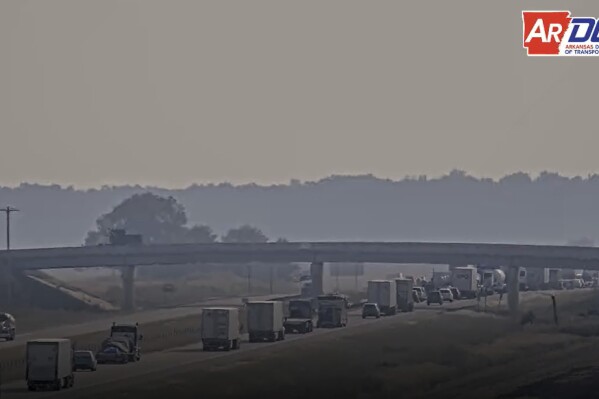 This traffic camera photo released by the Arkansas Department of Transportation shows traffic backed up after a deadly pileup on Highway 67 as smoke fills the air from a grass fire burning on Tuesday, Oct. 3, 2023, near Swifton, Ark. (Arkansas Department of Transportation via AP)