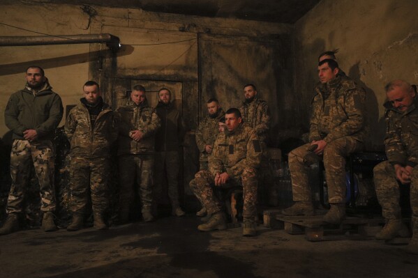 Ukrainian servicemen of the 72nd mechanized brigade listen to a prayer during the sacred liturgy before the upcoming Christmas at the frontline near Vuhledar, Ukraine, Friday, Dec. 15, 2023. (AP Photo/Valentyn Kuzan)