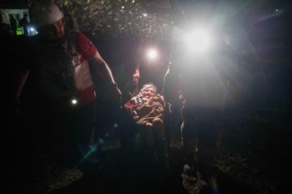 Rescue workers transport a woman on a makeshift stretcher outside of a house destroyed by a Russian airstrike in a residential neighborhood in Kyiv, Ukraine, on Thursday, April 24, 2025. (AP Photo/Evgeniy Maloletka)