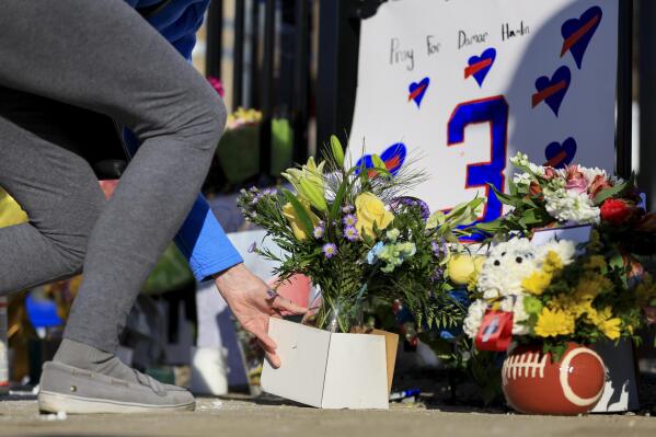 A person leaves flowers for the display set-up for Buffalo Bills' Damar Hamlin outside of University of Cincinnati Medical Center, Wednesday, Jan. 4, 2023, in Cincinnati. Hamlin was taken to the hospital after collapsing on the field during the Bill's NFL football game against the Cincinnati Bengals on Monday night. (AP Photo/Aaron Doster)