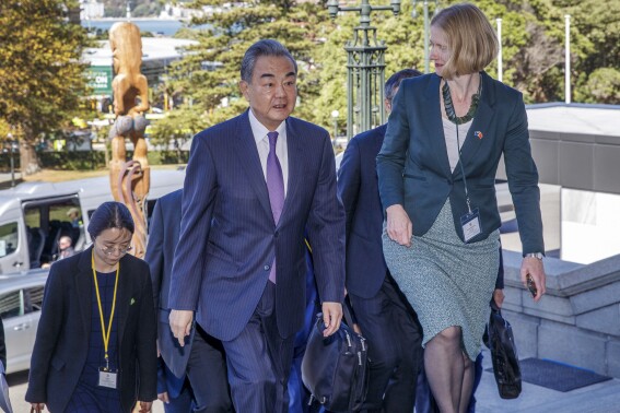 China's Minister of Foreign Affairs Wang Yi, center, is escorted up Parliament Steps by Ministry of Foreign Affairs and Trade North Asia divisional manager Wendy Matthews, right, ahead of a bilateral meeting with his New Zealand counterpart Winston Peters, in Wellington, New Zealand, Monday, March 18, 2024. (Mark Mitchell/Pool Photo via AP)