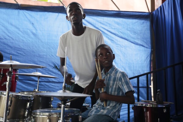 Woodberson Seide sits at the drum set as he studies with his music teacher drum Bijou Marc-Williamson at the Plezi Mizik Composition Futures School in Port-au-Prince, Haiti, Saturday, Sept. 23, 2023. “When I play drums, I feel proud,” Woodberson said. (AP Photo/Odelyn Joseph)