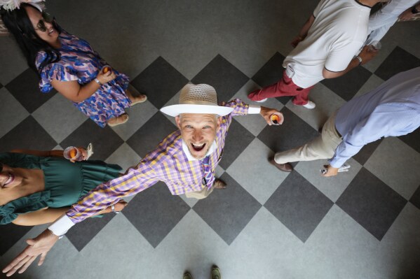 A race fan smiles at Churchill Downs before the 151st running of the Kentucky Oaks horse race Friday, May 2, 2025, in Louisville, Ky. (AP Photo/Charlie Riedel)