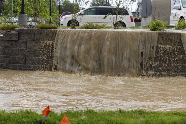 Water pours out of a parking lot onto the ground in Omaha, Neb. on Tuesday, May 21, 2024. (Chris Machian /Omaha World-Herald via AP)