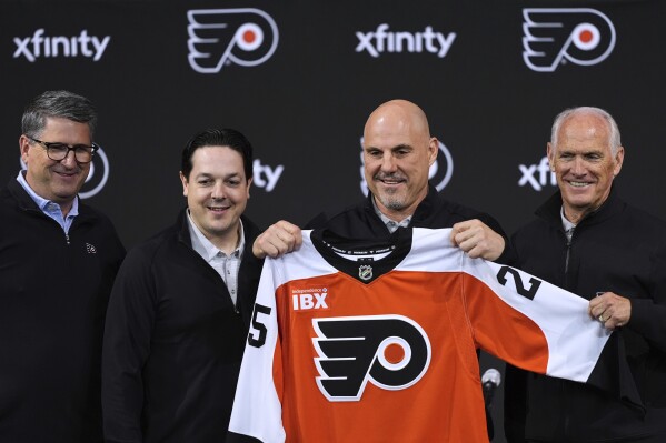 Philadelphia Flyers president Keith Jones, from left, general manager Daniel Briere, coach Rick Tocchet and governor Dan Hilferty pose for photographers after an introductory news conference at the NHL hockey team's arena, Friday, May 16, 2025, in Philadelphia. (AP Photo/Matt Slocum)