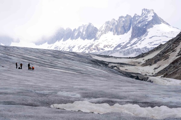 FILE - Swiss Federal Institute of Technology glaciologist and head of the Swiss measurement network 'Glamos', Matthias Huss, work at the Rhone glacier with his team near Goms, Switzerland, Friday, June 16, 2023. A top glacier watcher has warned that a warm early summer and a heat wave could have caused severe glacier melt across Switzerland, threatening to make 2023 the second-worst year for ice loss after a record thaw last year. (AP Photo/Matthias Schrader, File)