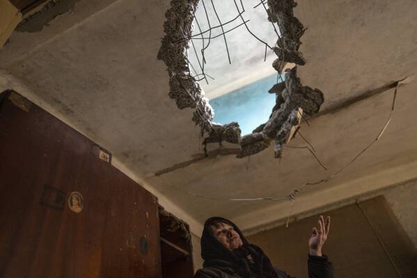 Halyna Falko, 52, talks to reporters while looking at the destruction caused after a Russian attack inside her house near Brovary, on the outskirts of Kyiv, Ukraine, Monday, March 28, 2022. (AP Photo/Rodrigo Abd)